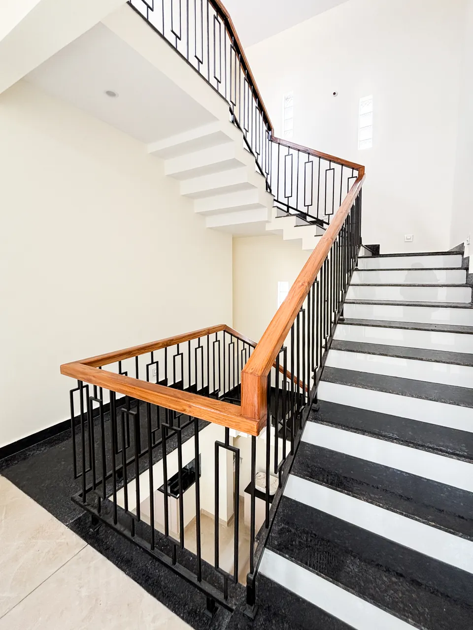 Granite and teak staircase with geometric iron balustrade